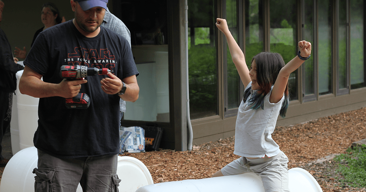 Two people put together a rain barrel