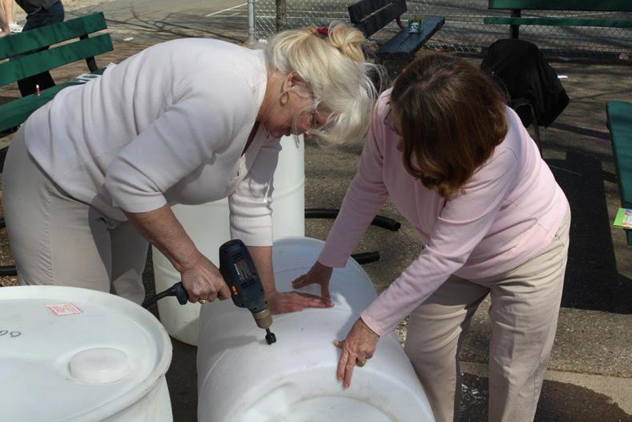 Two rain barrel builders work together at a workshop