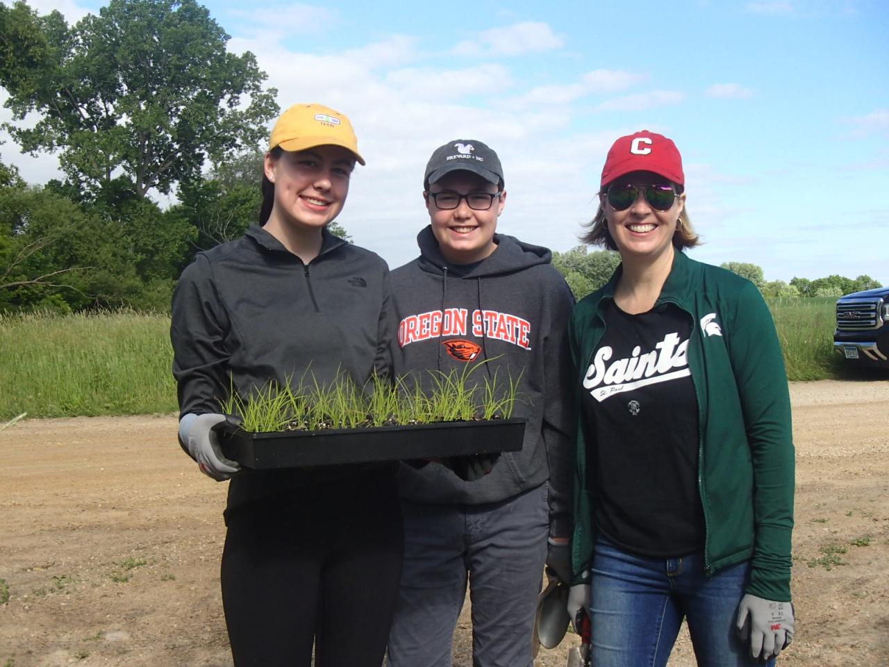 Three volunteers with a tray of plants ready to go in at South Creek from our June planting