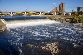 Water flows over the St. Anthony Falls Lock and Dam on a sunny day.