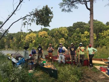 Volunteers stand by canoes on Settler's Island