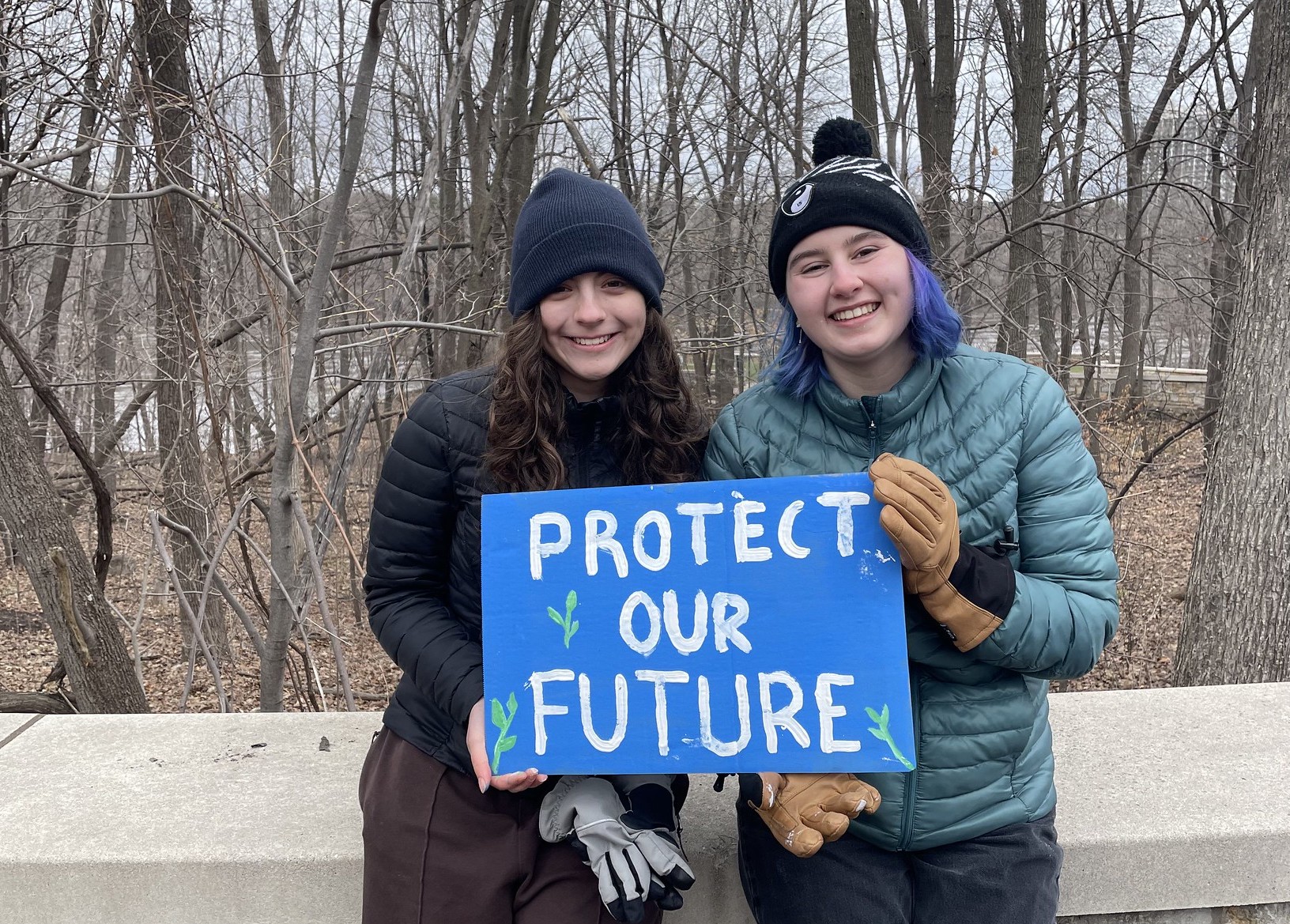 Two young people hold a sign in the river gorge that reads "Protect our future"